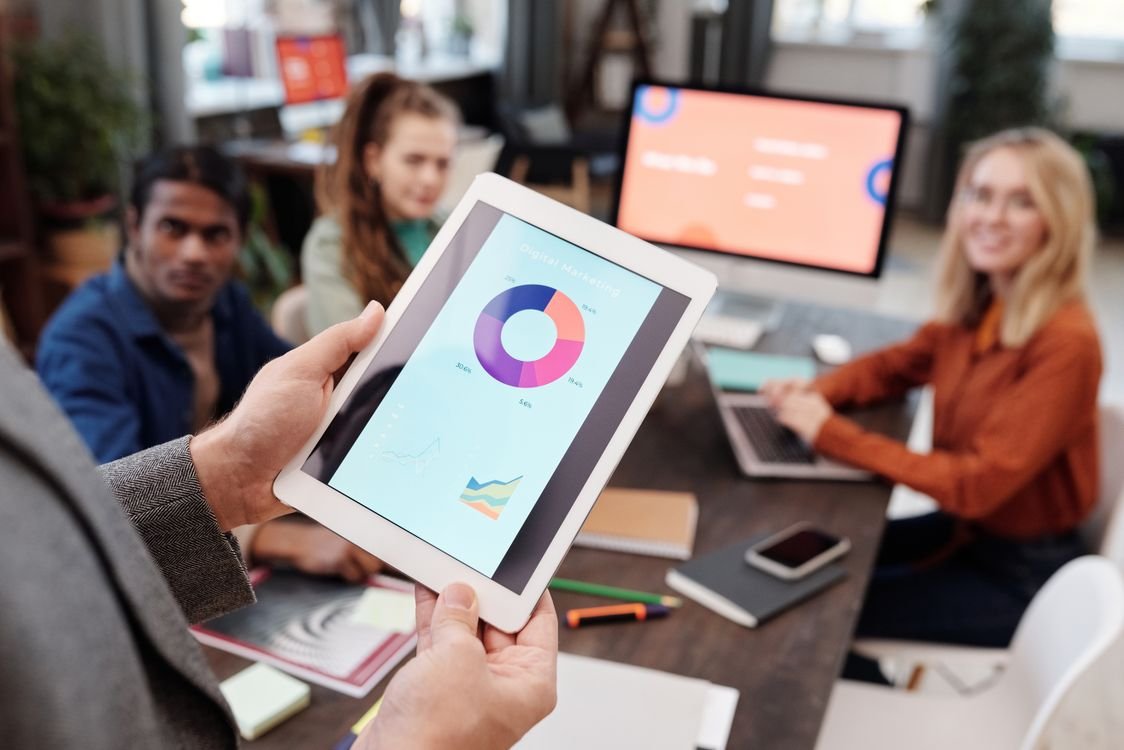 A business professional reviews a digital marketing analytics chart on a tablet in an office